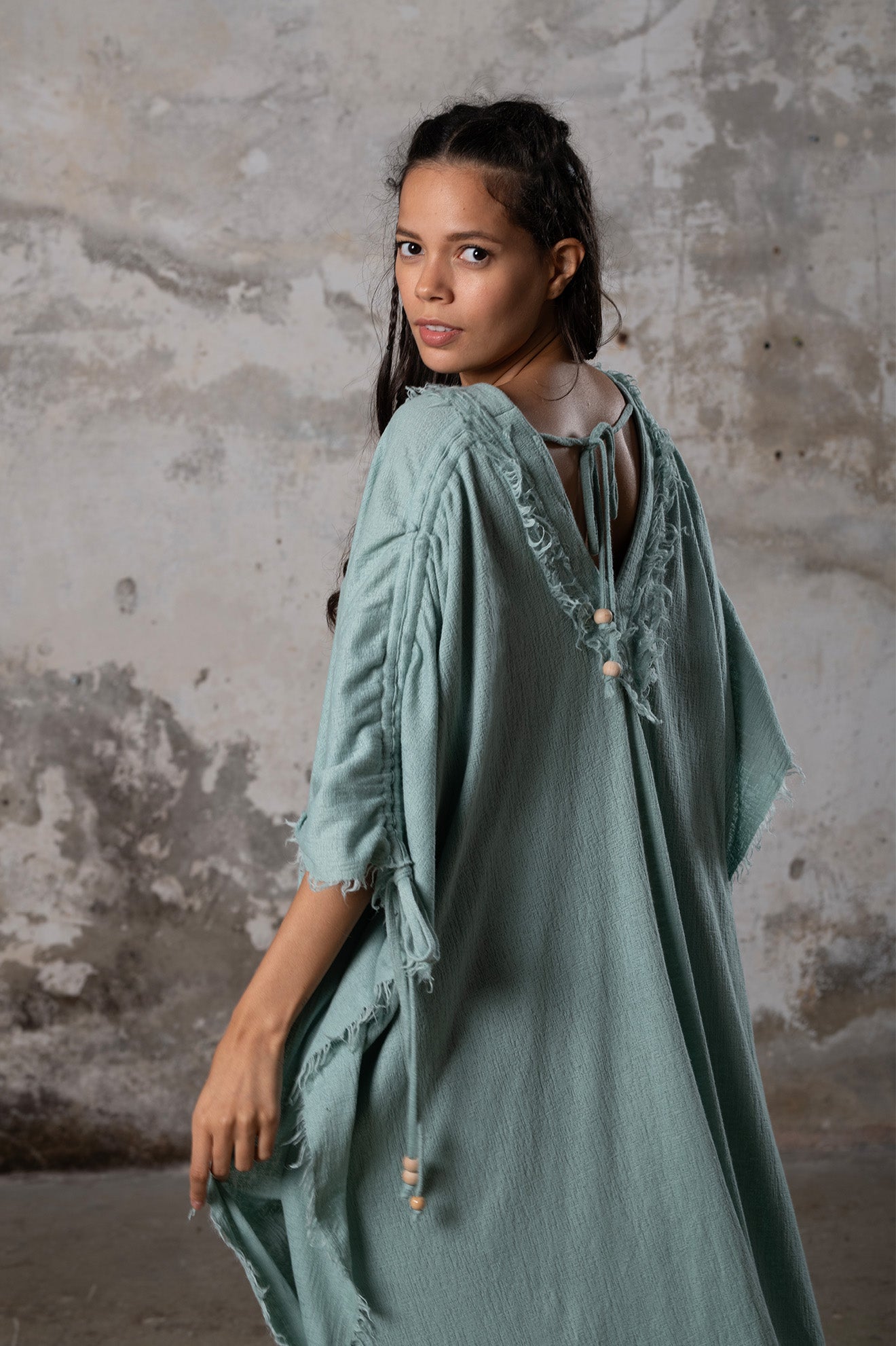 A versatile, earthy goddess dress that embodies boho-chic style. Crafted from the softest cotton fabric, this garment offers both comfort and a fashion statement. The dress can be worn in two distinct styles, either as a kaftan or a sultry dress, with a simple change in the way you put it on. Its natural and ethereal design exudes a warm, comforting feeling against your skin, making it a must-have addition to your wardrobe for those seeking a harmonious blend of style and comfort.